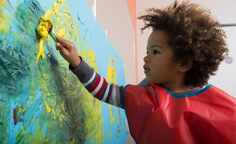 boy painting on wall yellow paint featured