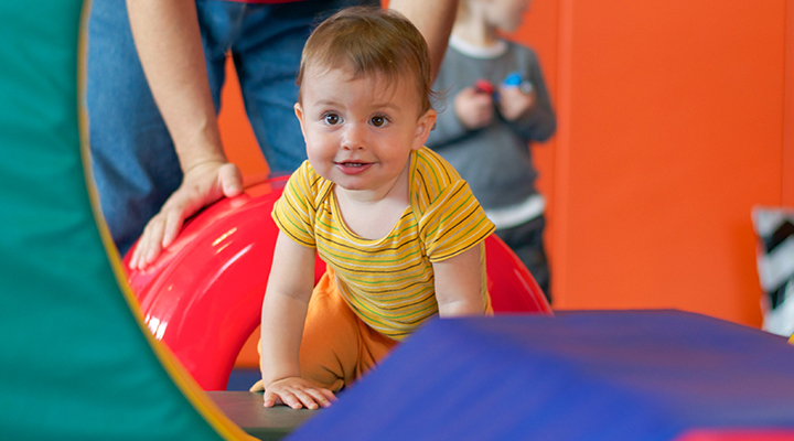 Baby climbing over soft foam gym equipment at Kidville Upper West Side