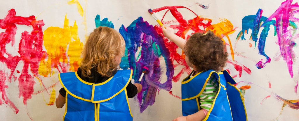 Children painting side by side on the giant paper painting wall in the Kidville art studio