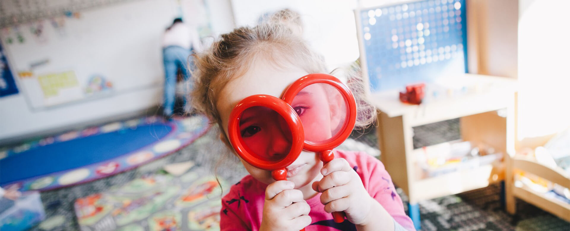 girl looking through magnifying glasses full width