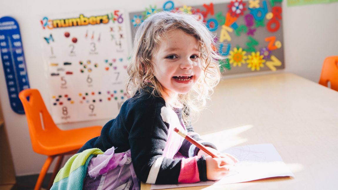 child smiling writing table preschool cta full width
